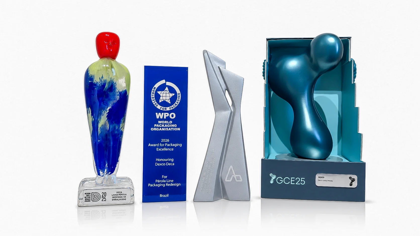 The project's four trophies side by side: Design for a Better World 2025, WorldStar from the World Packaging Organisation 2026, Prêmio ABRE and Grandes Cases de Embalagem 2025.