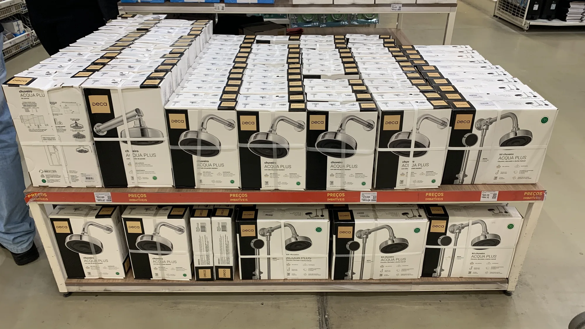 Pallet promocional com dezenas de caixas do Deca Acqua Plus em pé, lado a lado, na área de circulação de um home center.