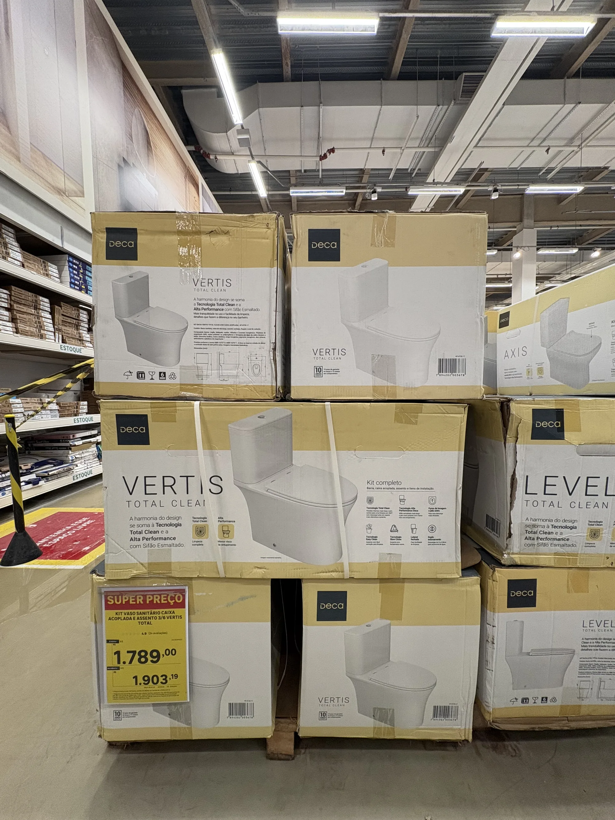 Caixas do Deca Vertis e do Deca Level empilhadas em três níveis, com etiqueta de super preço na frente e estoque de assentos ao fundo.