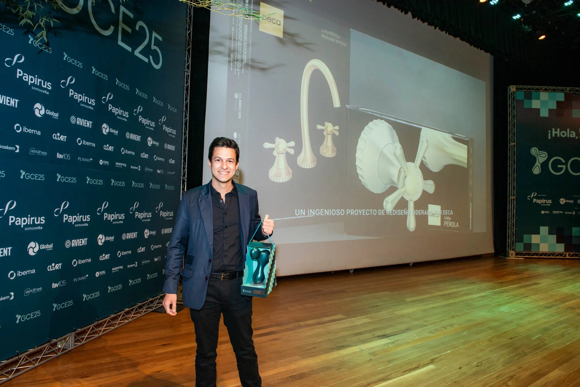 Hugo Zuffo alone on the Grandes Cases de Embalagem 2025 stage, trophy in hand and the Pérola Line projected on the screen behind him.
