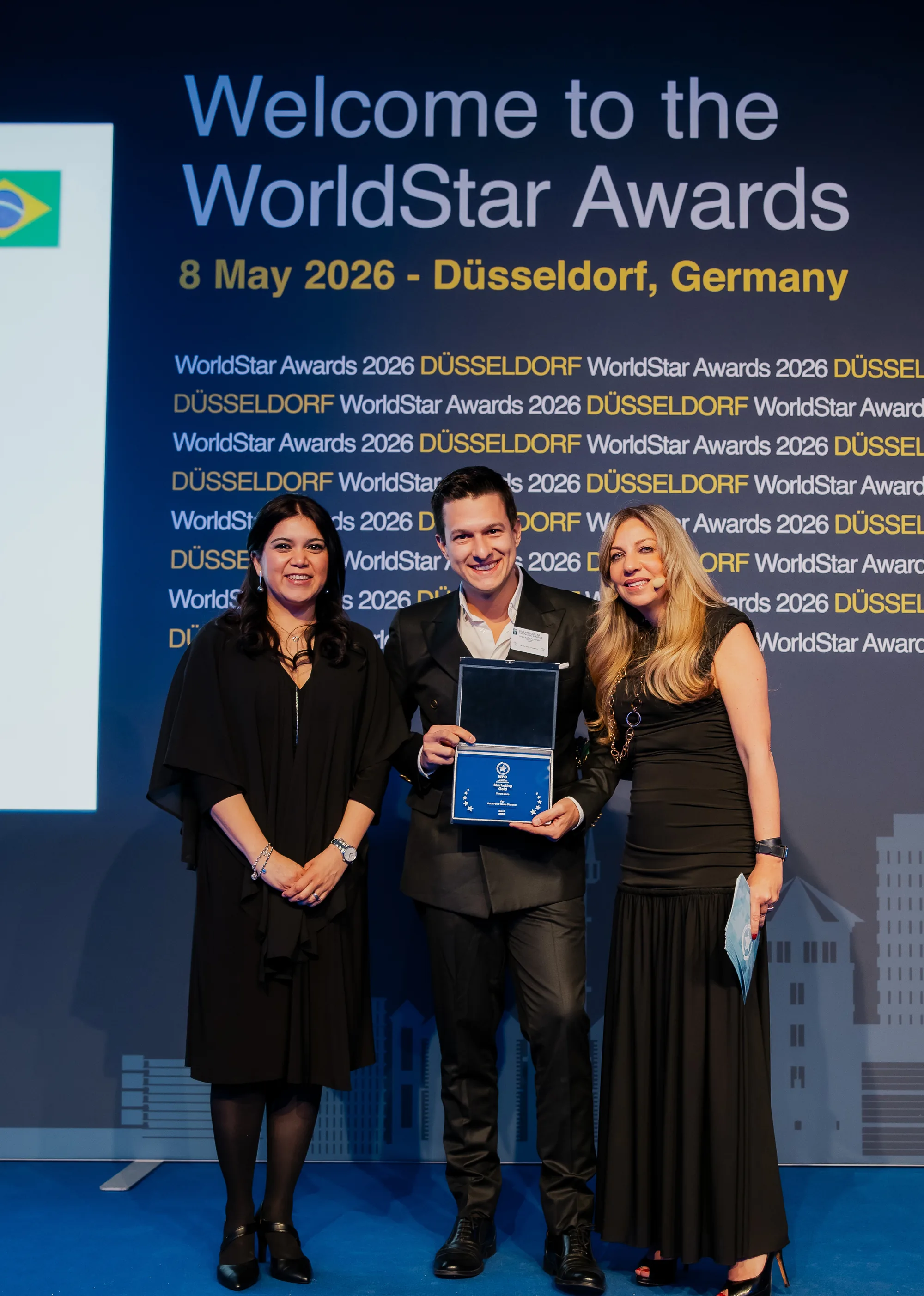 Hugo Zuffo holding the WorldStar Special Award for Marketing 2026 plaque, between two representatives of the organisation, on stage at the event in Düsseldorf.